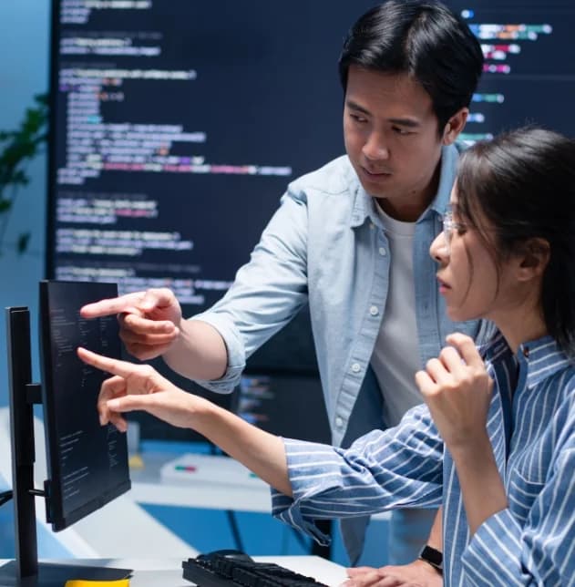 Two software engineers reviewing code together on a monitor